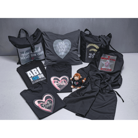 Verschiedene schwarze Textilien und Accessoires, darunter Taschen, Kissen, T-Shirts mit Aufdrucken und ein Plüschtier.