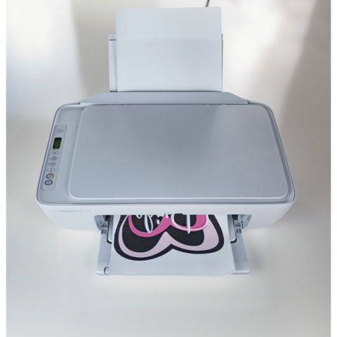 Ein Drucker mit einem Ausdruck eines pinken Herzens auf schwarzem Hintergrund. Der Drucker ist von oben sichtbar.